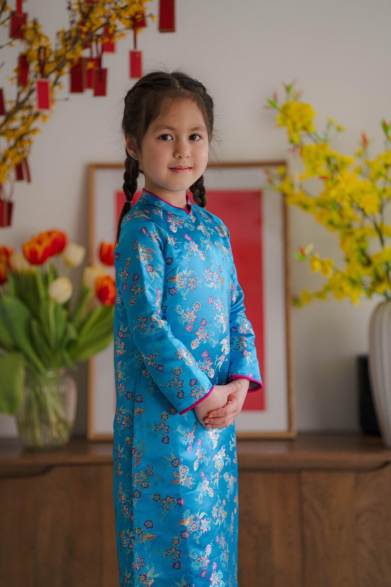 Enfant en áo dài bleu pour la fête du Têt, portrait en intérieur