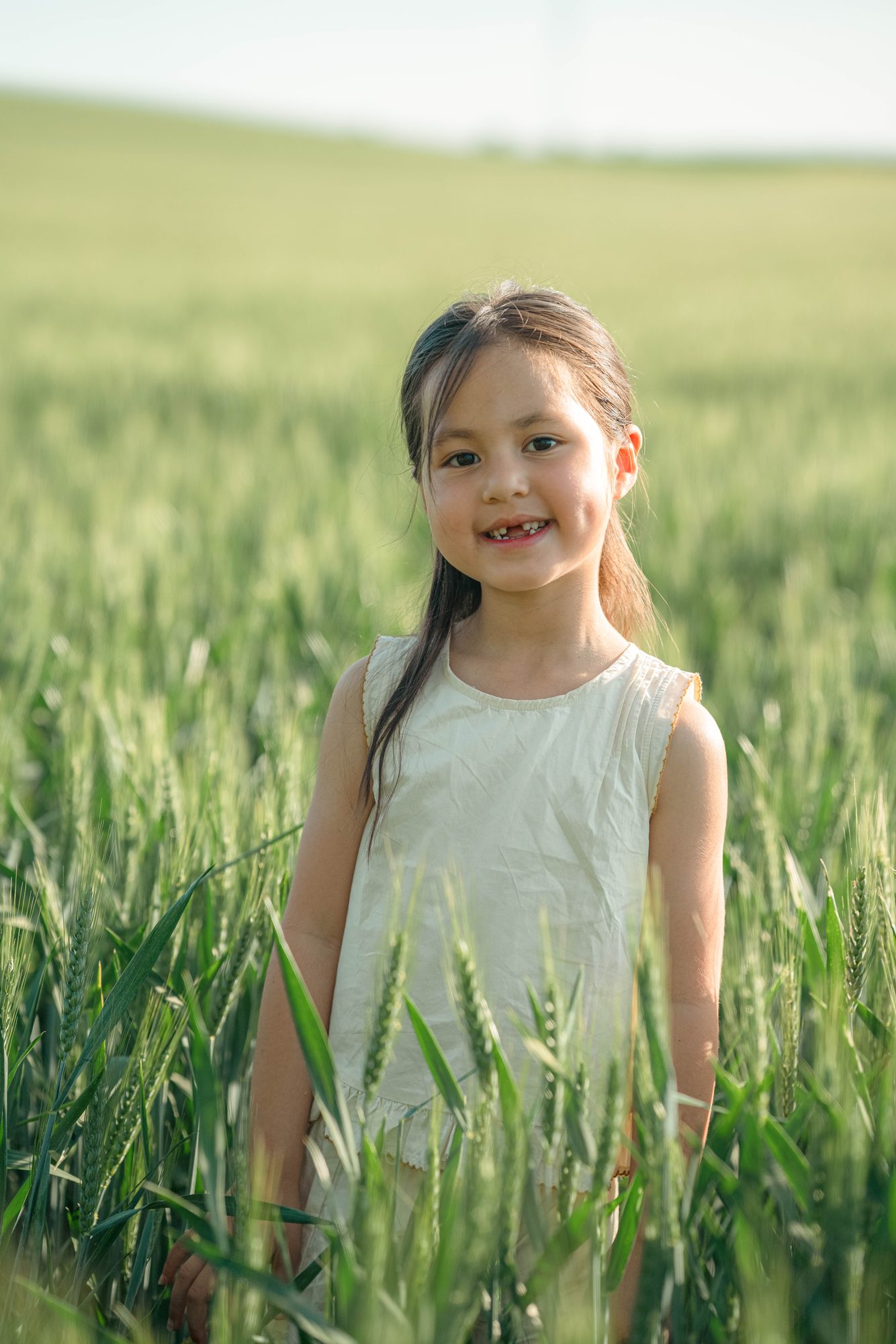 Enfant souriante dans un champ de blé vert, séance photo nature